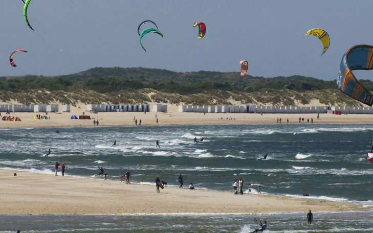 Sfeerbeeld Zeeuws-Vlaanderen: strand met strandhuisjes en kitesurfers